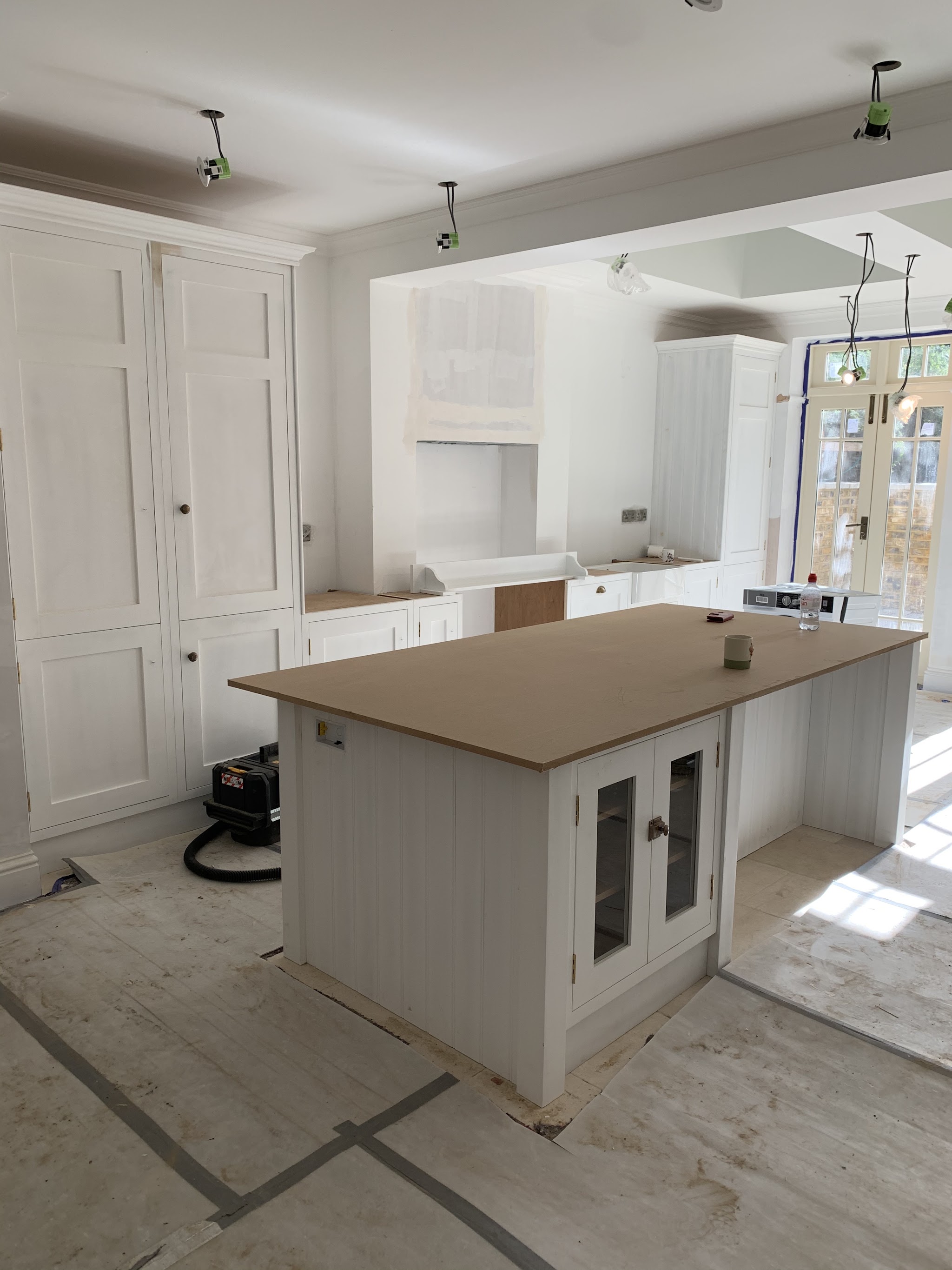 White painted kitchen and island taking shape, with pendant lights fitted