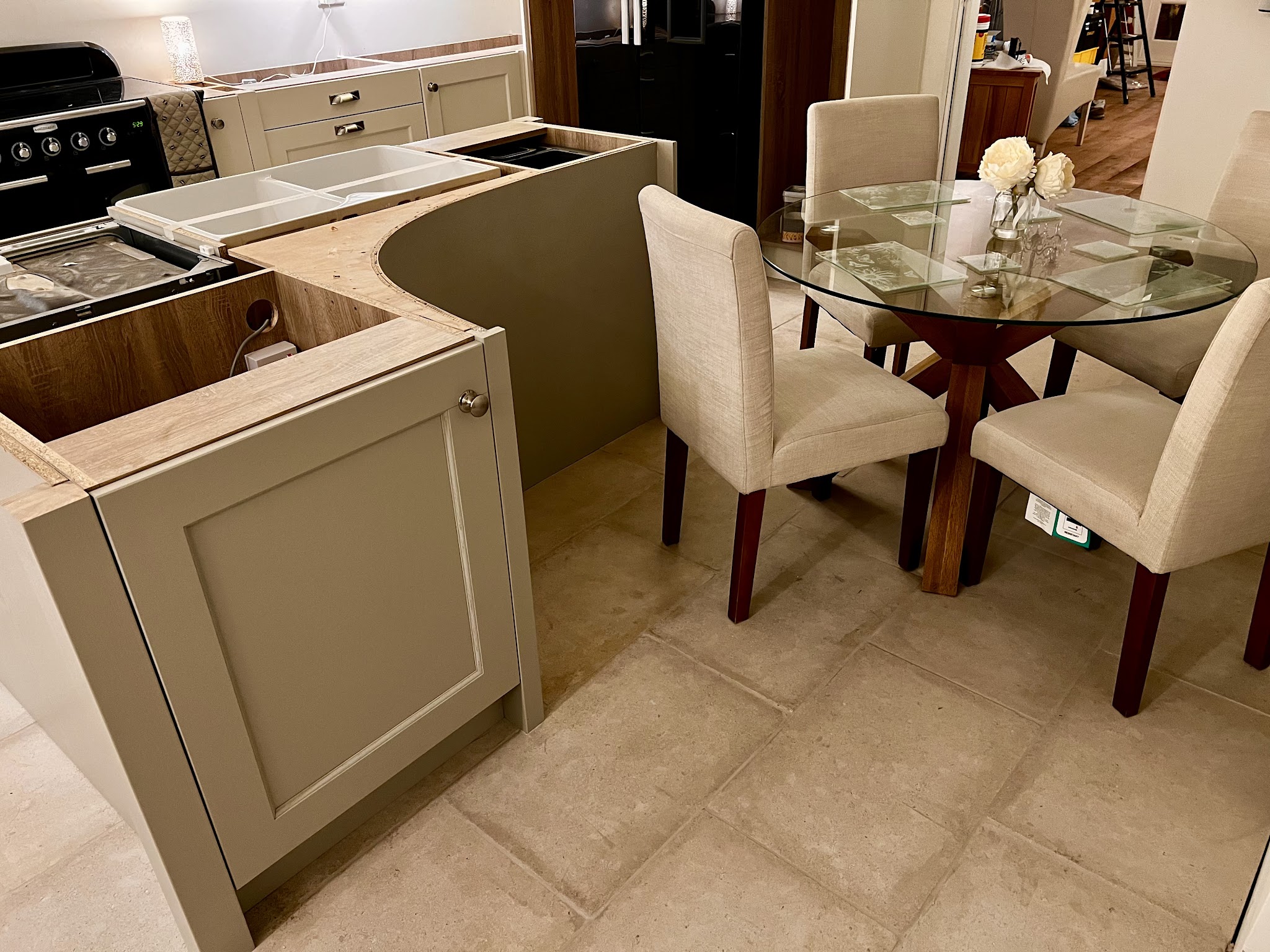 Curved kitchen island in sage shaker cabinetry beside a dining table