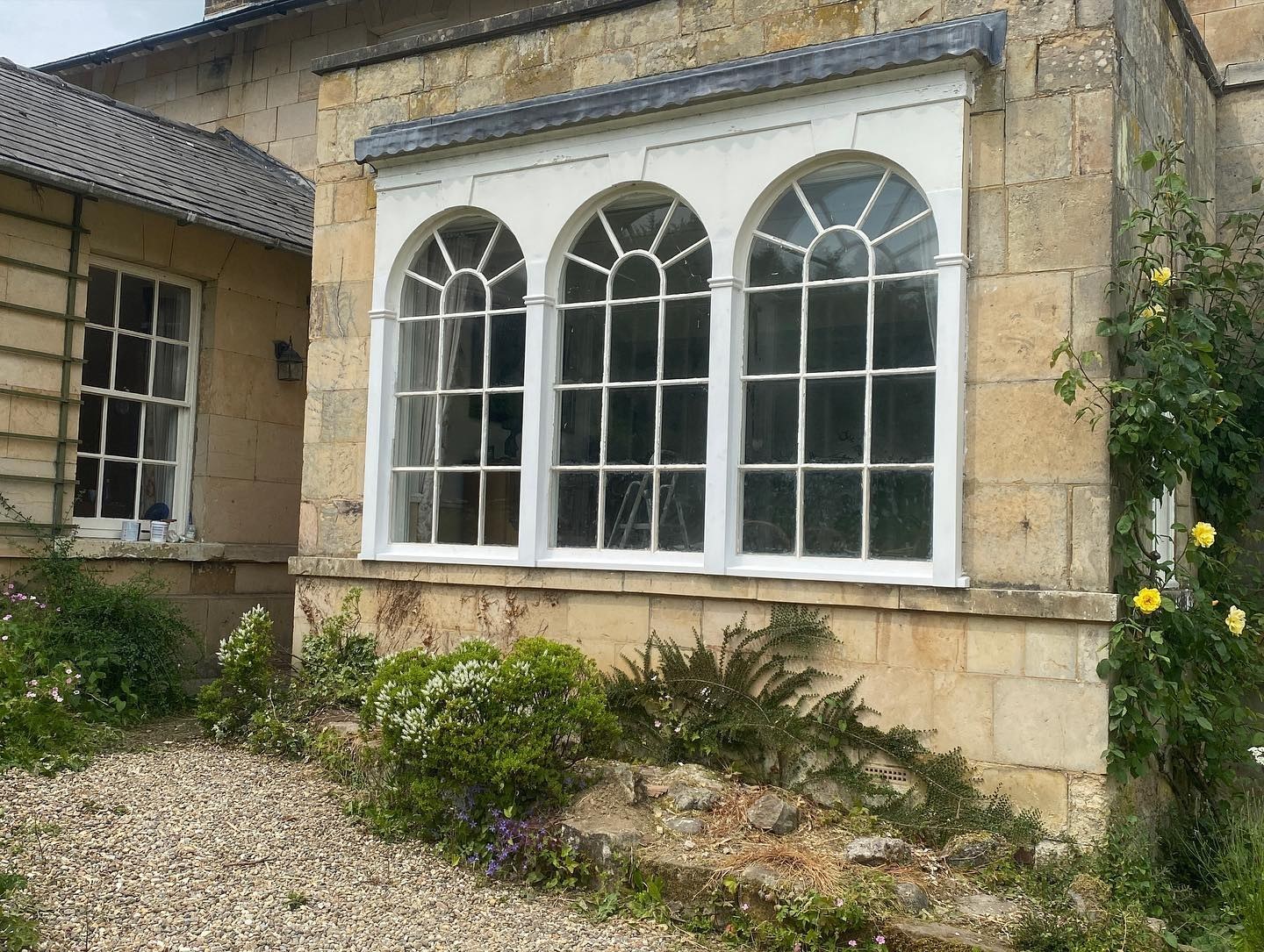 Arched windows on a stone house above a cottage garden