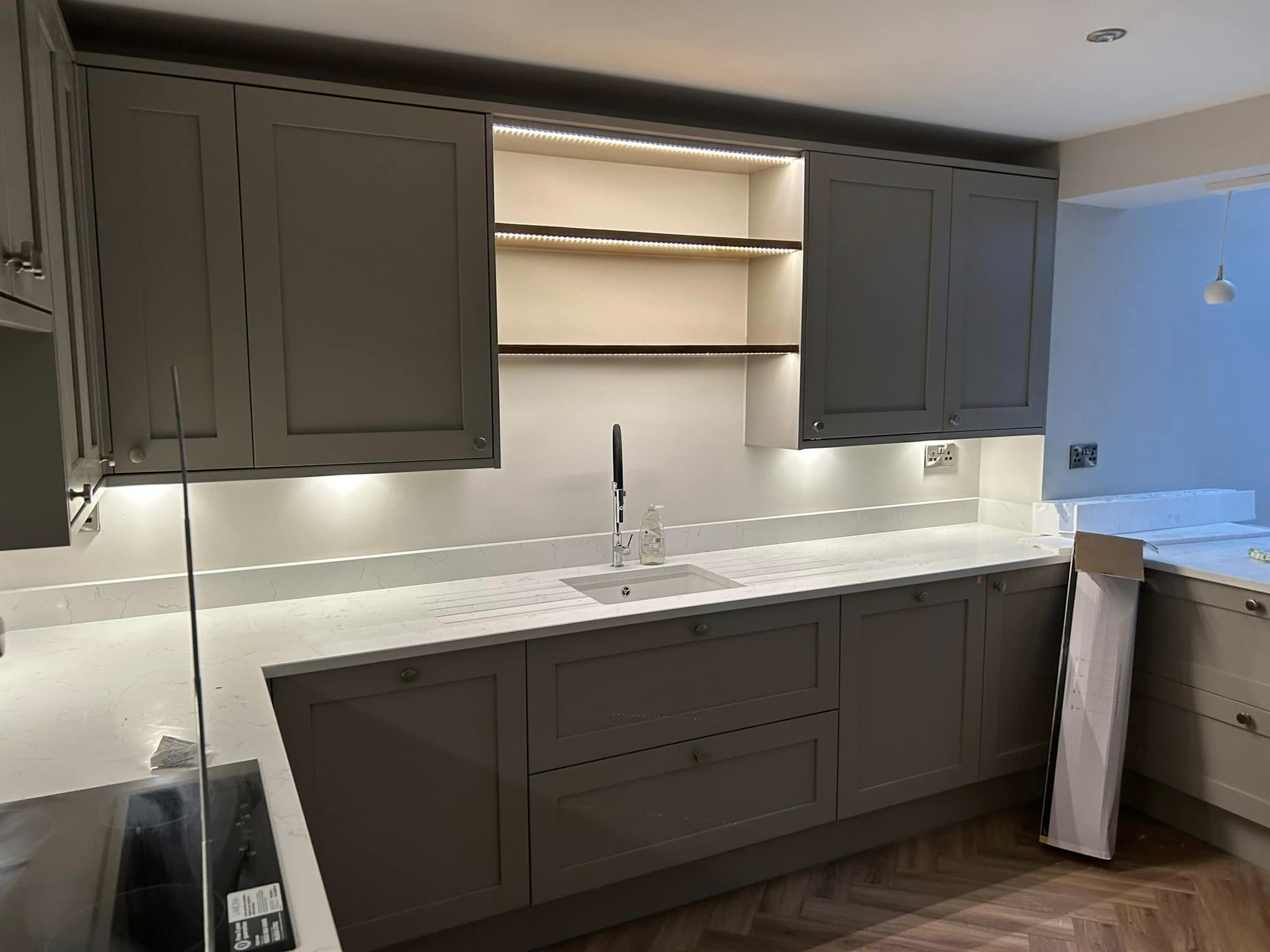 Dark grey shaker kitchen with lit open shelves and a white worktop
