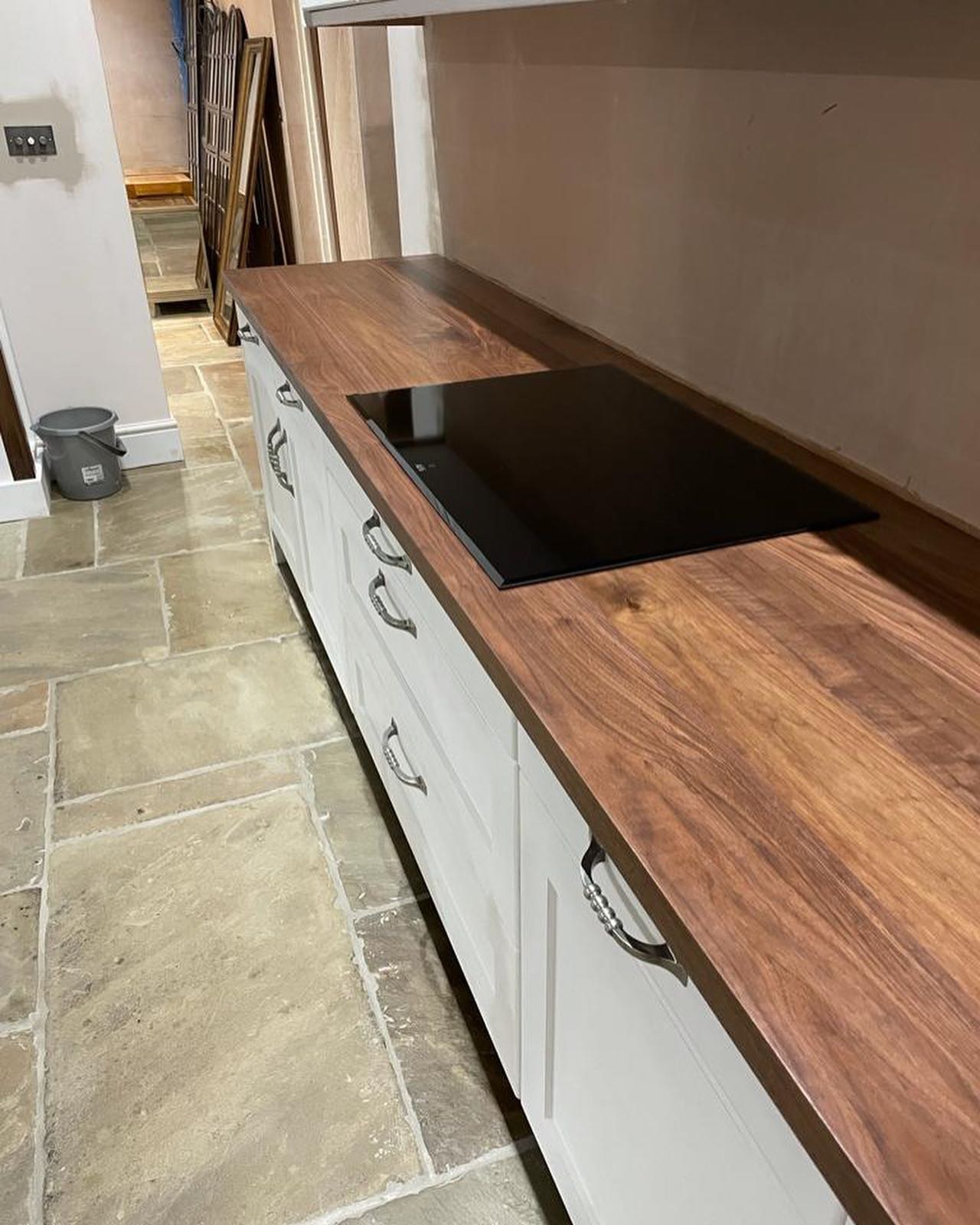 White shaker kitchen run with a dark walnut worktop on a flagstone floor