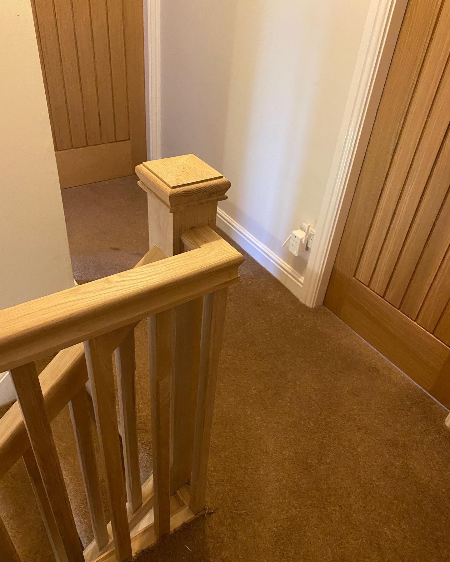 Oak newel and spindles on a landing with oak plank doors