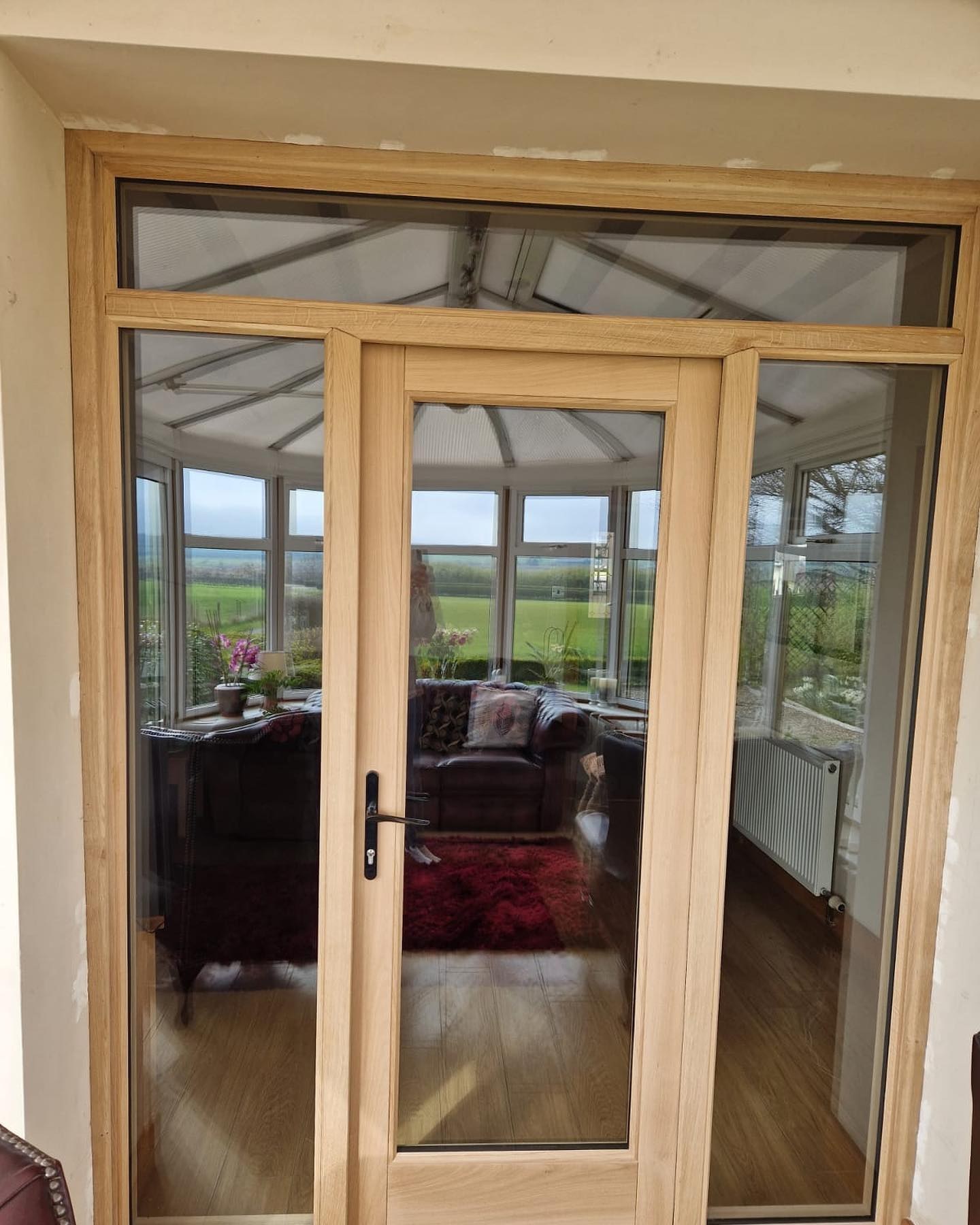 Glazed oak double doors with sidelights opening into a conservatory