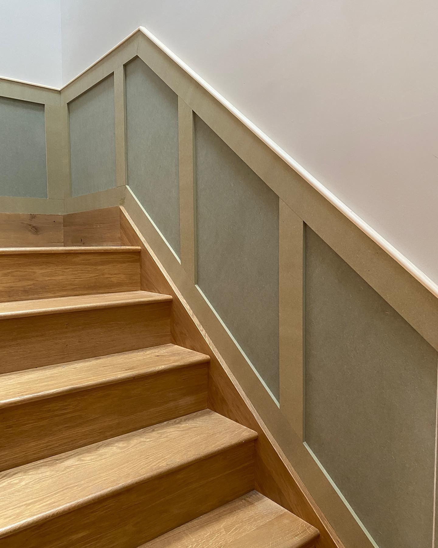 Oak stair treads with painted wall panelling alongside